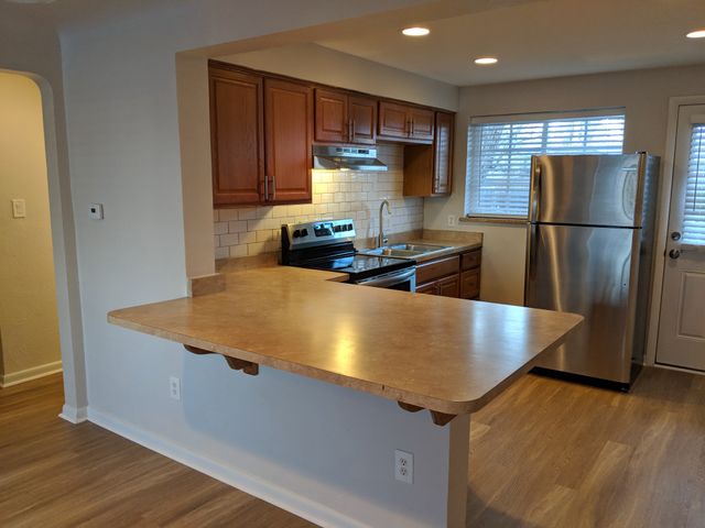 Modern kitchen with sleek stainless steel appliances, warm wooden cabinetry, and a spacious breakfast bar.