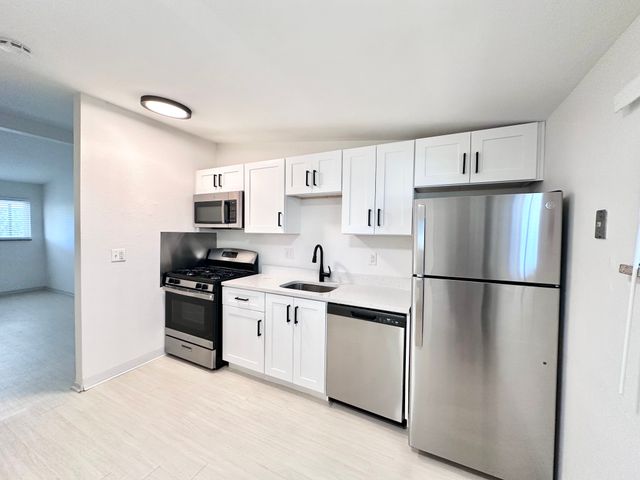 Modern kitchen with sleek white cabinets, stainless steel appliances, and a bright open layout.