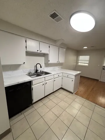 Modern kitchen with sleek white cabinets, dual sinks, and elegant tile flooring, perfect for culinary creativity.
