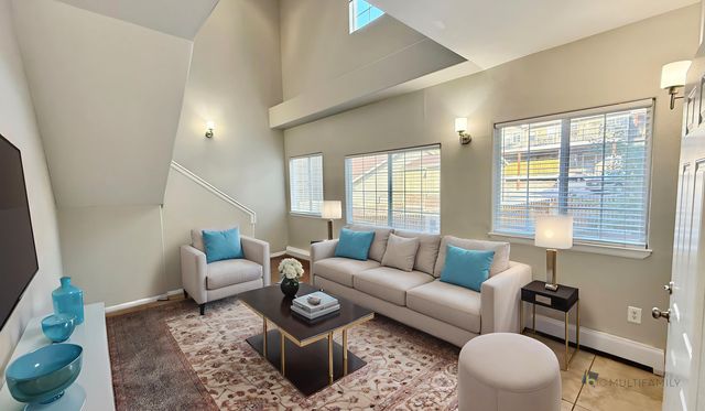 Bright and inviting living room with high ceilings, stylish furniture, and large windows offering natural light.