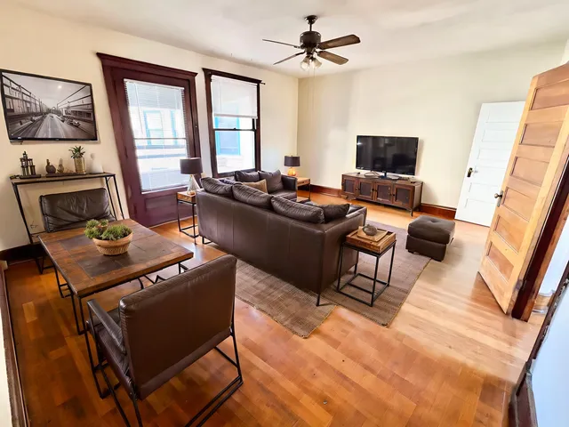 Inviting living room with rustic charm, featuring leather seating, a wooden coffee table, and large windows for natural light.