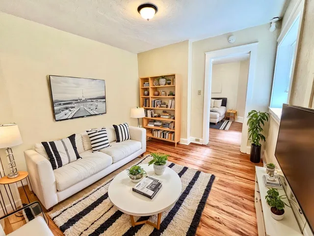 Bright and inviting living room with modern decor, stylish white sofa, and cozy ambiance, showcasing a spacious layout with elegant wooden flooring.