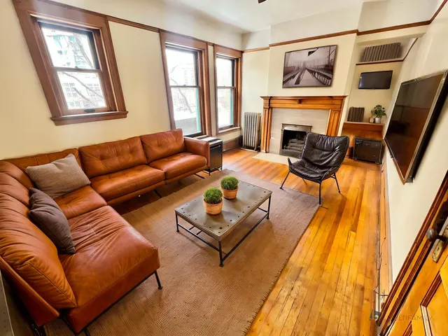 Inviting living room with rich leather sectional, elegant decor, and a cozy fireplace, offering a perfect space for relaxation and entertainment.