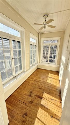 Charming sunlit room with large windows and elegant wooden flooring, perfect for relaxation or a cozy reading nook.
