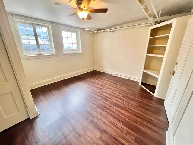 Bright and inviting room featuring rich hardwood floors, built-in shelving, and large windows for natural light.