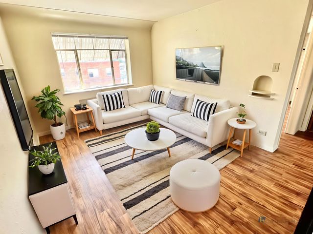 Bright and modern living room with a cozy white sofa, stylish decor, and hardwood floors.