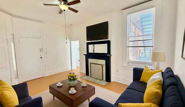 Bright and inviting living room with a cozy fireplace, plush navy sofa with vibrant yellow cushions, and stylish coffee table adorned with floral decor.