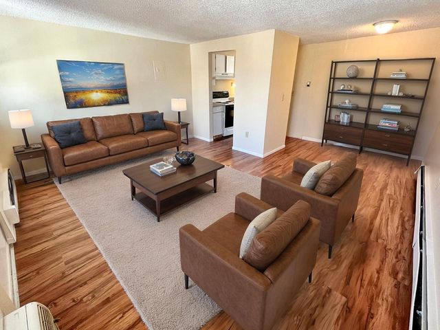 Inviting living room with cozy leather seating, open bookshelf, and warm wood flooring, exuding comfort and style.
