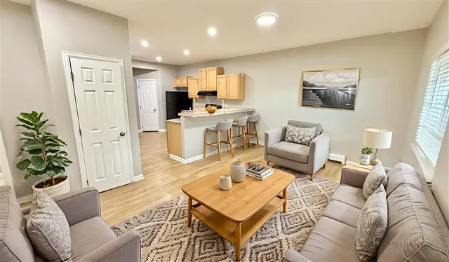 Inviting living area with modern decor featuring plush seating, a stylish coffee table, and an open-plan kitchen with breakfast bar and seating.