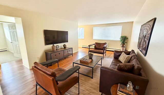 Warm and inviting living room with leather furniture, large wall-mounted TV, and expansive windows allowing natural light.