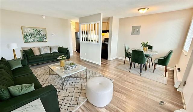 Inviting open-concept living space with elegant green sofa, modern coffee table, and cozy dining area with chic green chairs.