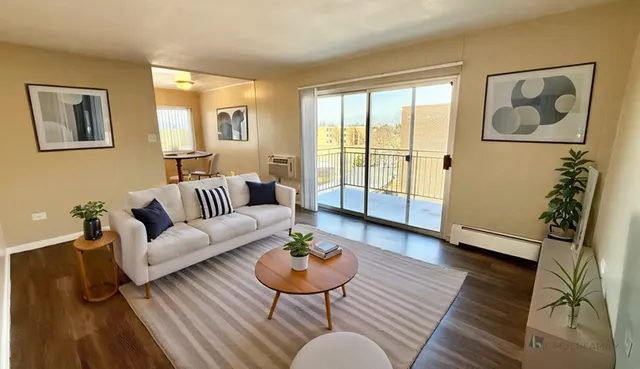 Bright and airy living room with modern decor, sliding glass doors opening to a balcony, and cozy furniture setup.