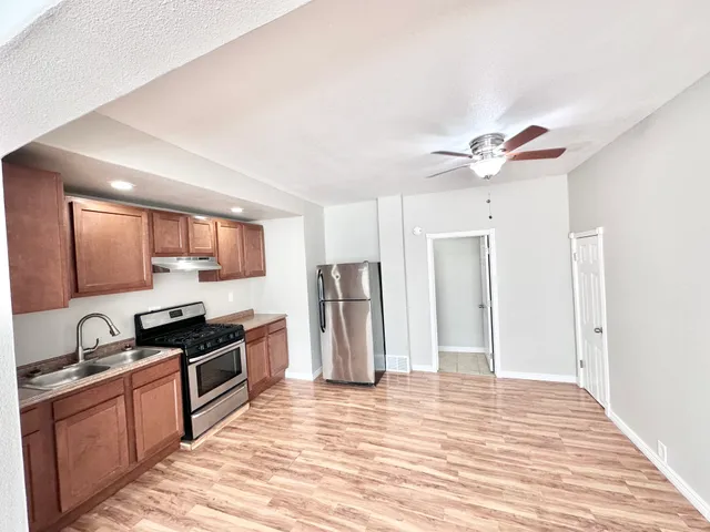 Charming apartment kitchen with modern stainless steel appliances, sleek wooden cabinets, and elegant hardwood flooring.