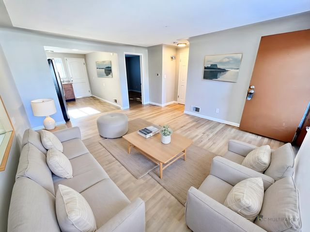 Inviting living room with modern decor, featuring a comfortable sofa, stylish armchairs, and a sleek coffee table on warm wood flooring.