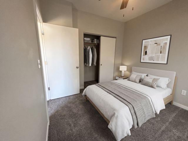Cozy modern bedroom with plush carpeting, elegant bed setup, and stylish decor, offering a serene and inviting atmosphere.