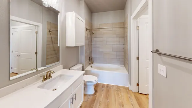 Modern bathroom featuring elegant fixtures, subway-tiled bathtub, and sleek vanity with ample storage.