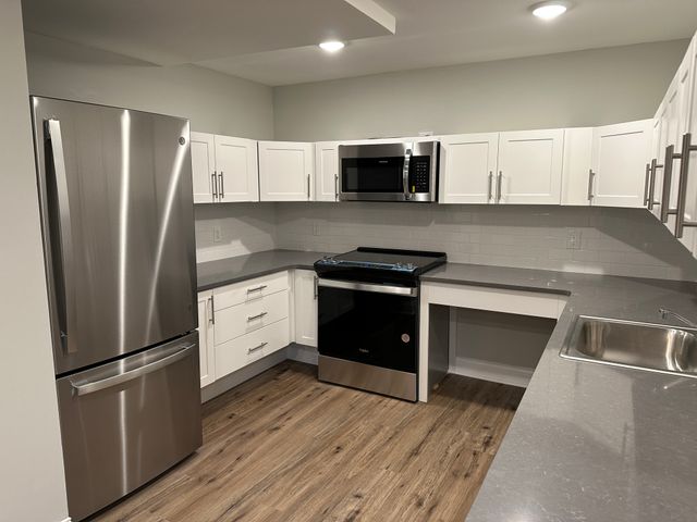 Modern kitchen with sleek stainless steel appliances, white cabinetry, and elegant gray countertops.