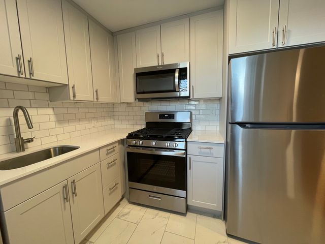 Modern kitchen with sleek stainless steel appliances, white cabinetry, and subway tile backsplash.