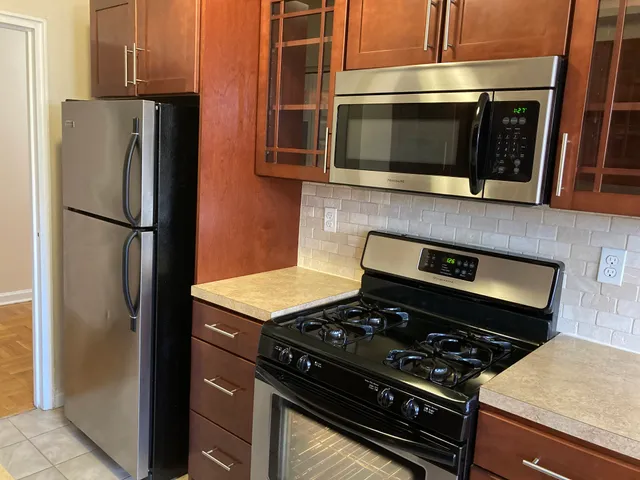 Modern kitchen with stainless steel appliances, elegant wooden cabinetry, and a smooth tiled floor.