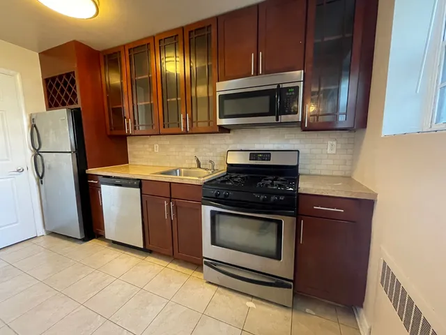 Modern kitchen with stainless steel appliances, elegant wooden cabinetry, and sleek tile flooring.