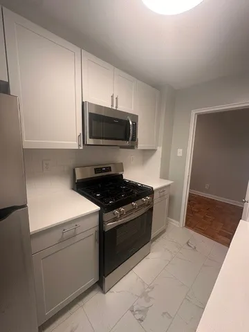 Modern kitchen with sleek cabinetry, stainless steel appliances, and elegant tile flooring.