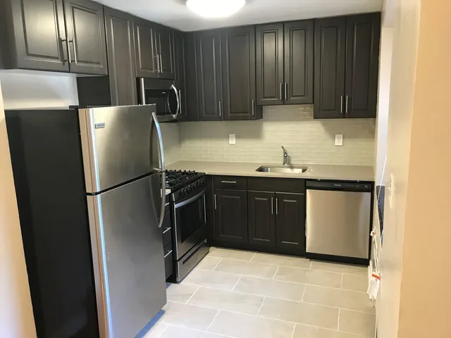 Modern kitchen with sleek dark cabinets, stainless steel appliances, and elegant tiling.