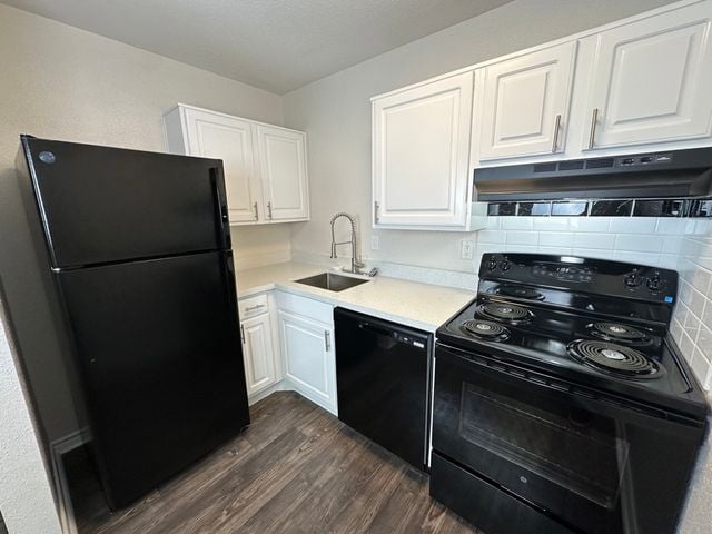 Modern kitchen with sleek black appliances, elegant white cabinetry, and a glossy quartz countertop, offering a blend of style and functionality.