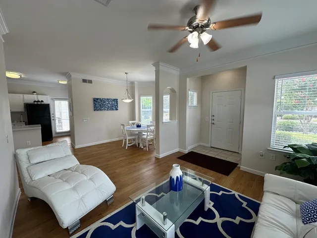Bright and inviting living room with elegant composite wood floors, modern white furniture, and a chic dining area adjacent to the kitchen.