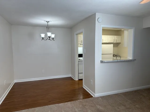 Bright dining area with elegant chandelier adjacent to an open kitchen featuring white cabinets and modern appliances.