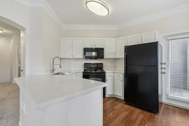 Modern kitchen with sleek white cabinets, black appliances, and elegant countertops.