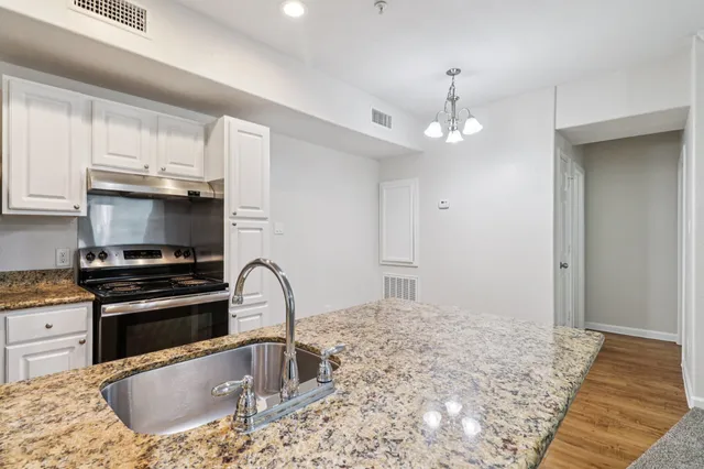 Modern kitchen with granite countertops, sleek stainless steel appliances, and elegant lighting fixtures, offering a warm and inviting atmosphere.