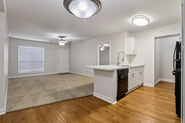 Bright and inviting open-concept living and kitchen area featuring modern lighting, sleek quartz countertops, and stylish wood-style flooring.