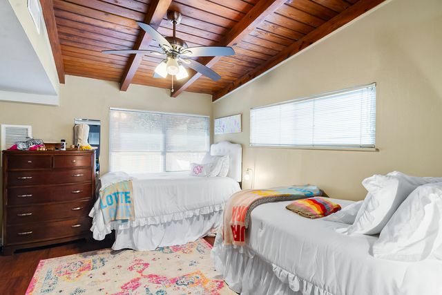 Charming bedroom with two cozy twin beds, wooden ceiling, and colorful accents creating a warm, inviting space.