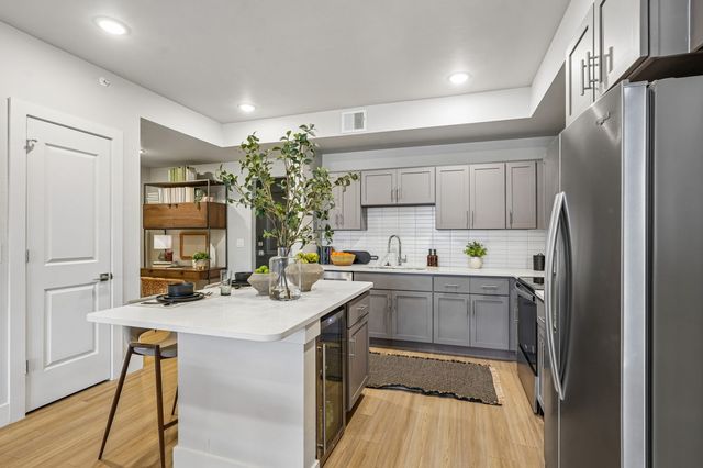Modern kitchen featuring sleek grey cabinets, stainless steel appliances, and a stylish island with a cozy seating area.
