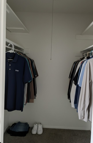 Spacious walk-in closet featuring organized shelving, neatly hung clothes, and stylish decor.