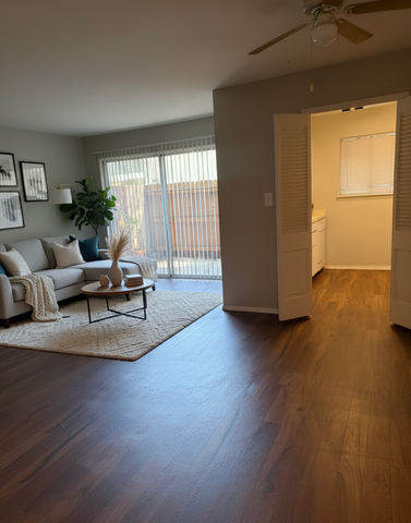 Inviting living room with elegant wood flooring, cozy gray sofa, chic decor, and ample natural light from large sliding doors.