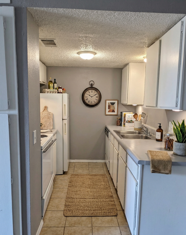 Charming and cozy kitchen with modern white cabinetry, stylish decor, and efficient appliances in an inviting apartment.