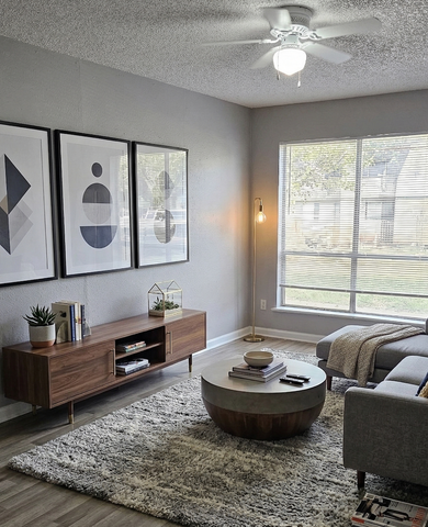 Chic living room with modern decor, featuring a cozy gray sectional, stylish coffee table, and large window for natural light.