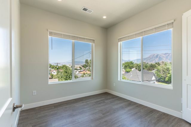 Bright room with large windows showcasing a stunning mountain and suburban view, featuring modern wood flooring and soft neutral walls.