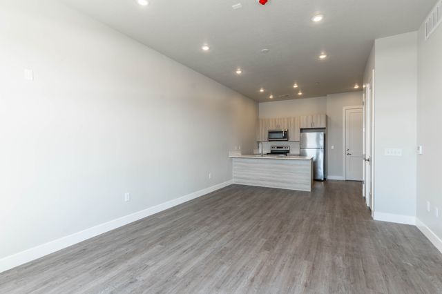 Modern open-concept living space featuring sleek kitchen with stainless steel appliances and stylish wood flooring.
