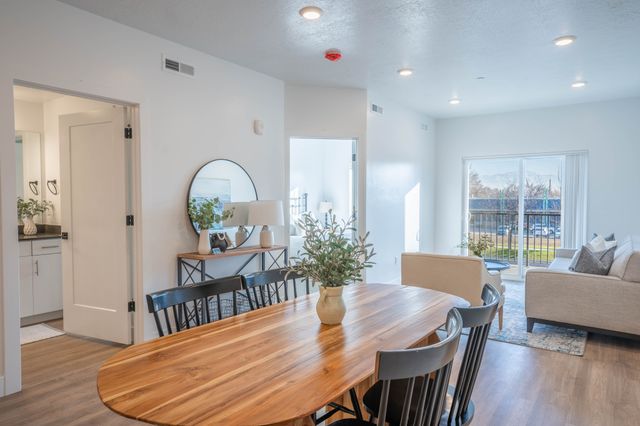 Bright and inviting open-concept living space with stylish dining area, cozy sofa, and natural light from a sliding glass door leading to a balcony.