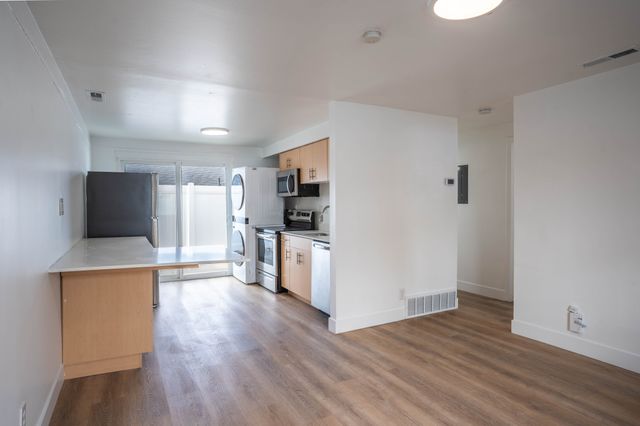Chic apartment kitchen with modern appliances, wood flooring, and abundant natural light.