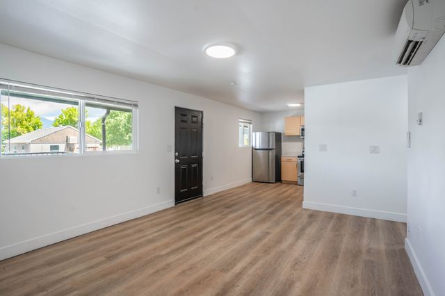 Bright open-plan living area with modern wood flooring, stainless steel appliances, and large windows offering natural light.