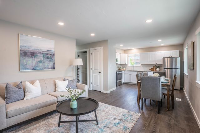 Charming open-concept living room and kitchen with modern decor, cozy seating, and sleek stainless steel appliances.