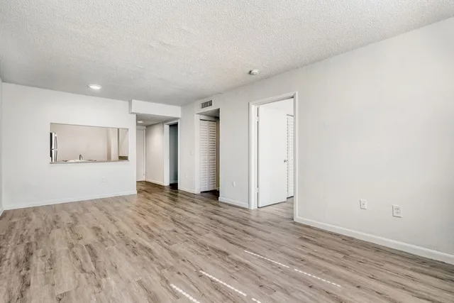 Bright and spacious living area with elegant wood flooring and open kitchen access.