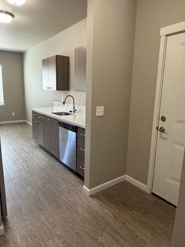 Modern kitchen with sleek cabinetry, stainless steel appliances, and elegant wood flooring.