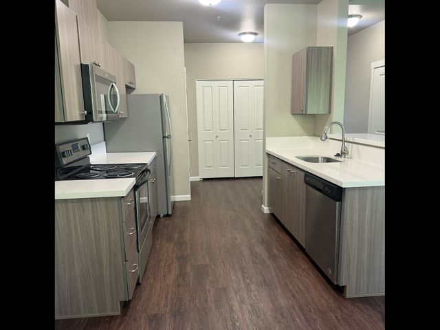 Modern kitchen with sleek cabinetry, stainless steel appliances, and rich wood flooring, offering a blend of style and functionality.