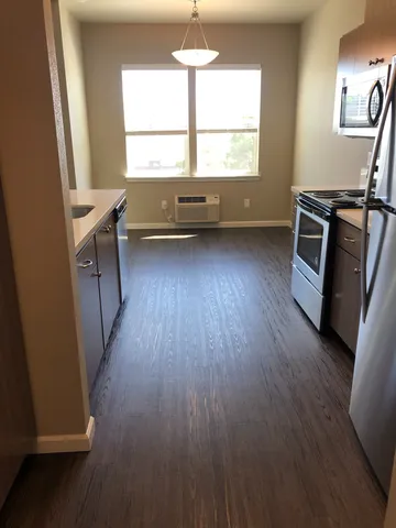 Bright and inviting kitchen with modern appliances, elegant cabinetry, and large windows providing abundant natural light on gleaming wooden floors.