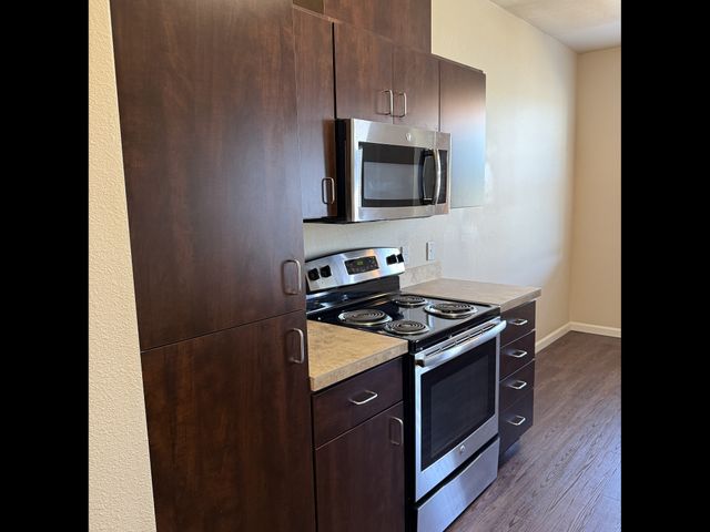 Elegant kitchen featuring dark wood cabinets, sleek stainless steel appliances, and rich hardwood flooring.