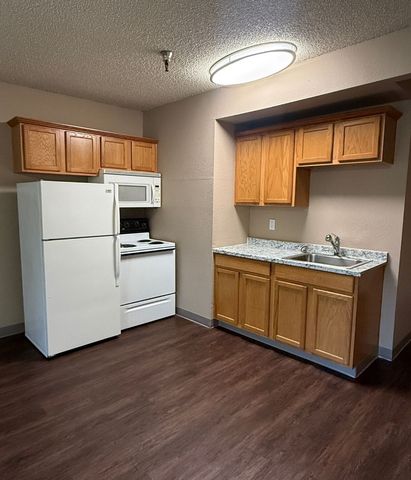 Charming kitchen with modern appliances, warm wooden cabinets, and sleek countertops on rich hardwood flooring.